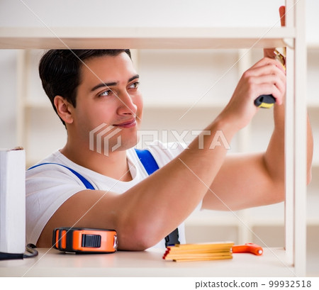 Worker man repairing assembling bookshelf Worker man repairing assembling bookshelf 99932518