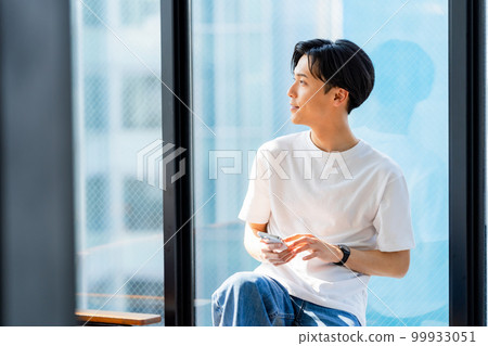A young man operating a smartphone 99933051