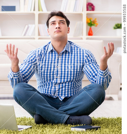 Young handsome man sitting on floor at home 99933588