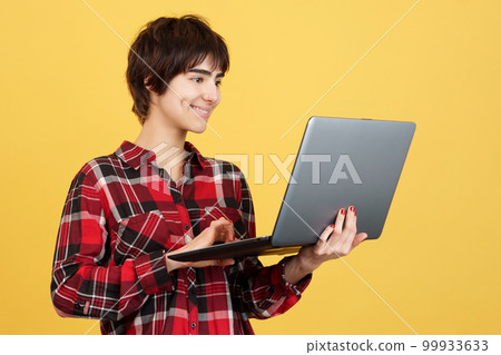Androgynous person smiling while using a laptop Androgynous person smiling while using a laptop 99933633