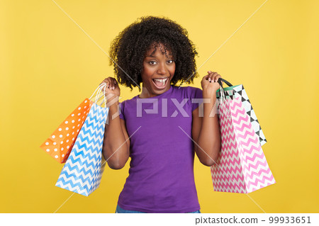 Happy woman with curly hair holding shopping bags 99933651