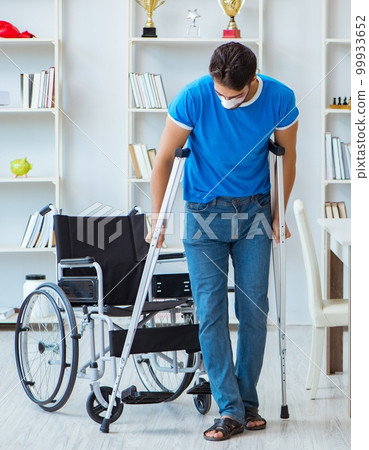 Young man recovering after surgery at home with crutches and a w 99933652