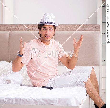 Man with suitcase in bedroom waiting for trip 99934164