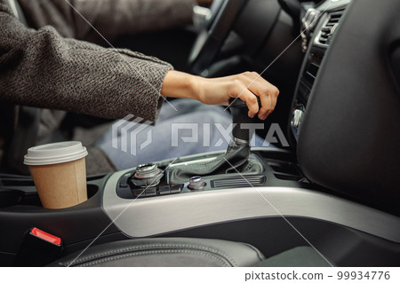Close up of woman change speed holding hand on gearbox in the car Close up of woman change speed holding hand on gearbox in the car 99934776