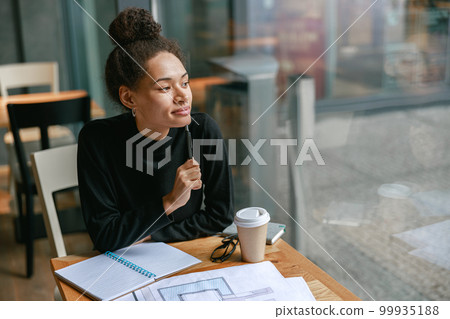 Thoughtful woman architect looking at window while working in cafe. Distance work concept 99935188