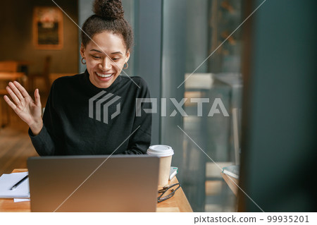 Smiling woman freelance talking with client via video call and discuss project sitting in cafe 99935201