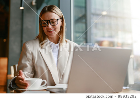 Successful businesswoman having coffee break time during working day in cafe. Distance work concept Successful businesswoman having coffee break time during working day in cafe. Distance work concept 99935292