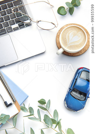 Modern white office desk table with laptop, notebook, toy car and other supplies. Modern white office desk table with laptop, notebook, toy car and other supplies. 99935599