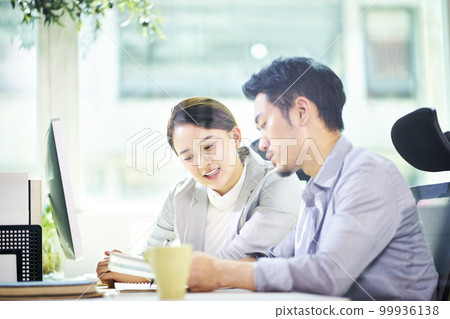 asian business man and woman working together in office using tablet PC. 99936138