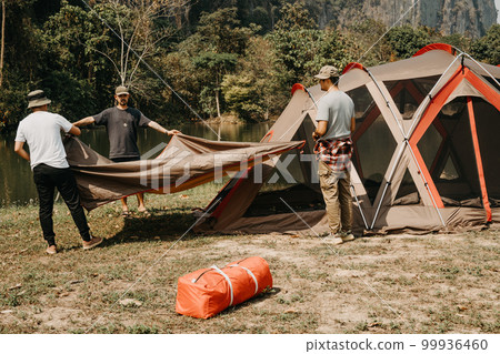 Young men help set up tents for camping. 99936460
