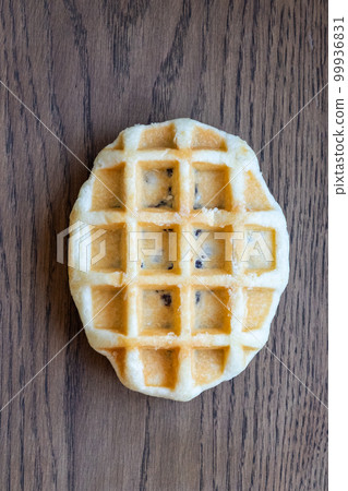 Delicious fresh waffle with chocolate filling lies on a wooden table. vertical photo Delicious fresh waffle with chocolate filling lies on a wooden table. vertical photo 99936831