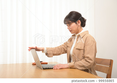 Woman opening (closing) laptop at desk 99938865