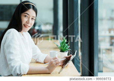 Portrait of a beautiful Asian teenage girl using a tablet computer. 99939772