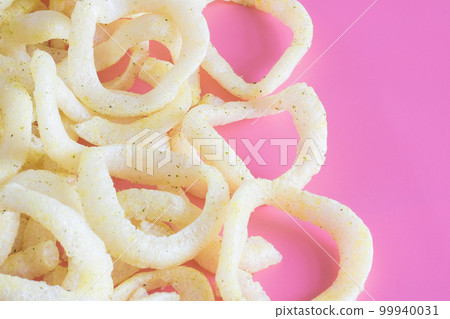 A bunch of crunchy onion rings close up on a pink background. Snack onion rings. 99940031