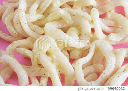 A bunch of crunchy onion rings close up on a pink background. Snack onion rings. 99940032