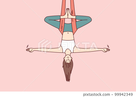 Woman doing aerial yoga hangs upside down in hammock and keeps balance with arms at sides Woman doing aerial yoga hangs upside down in hammock and keeps balance with arms at sides 99942349
