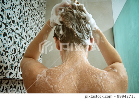 Back view of naked woman taking shower in shower stall. Woman washing her hairs in bathroom. Morning hygiene 99942713