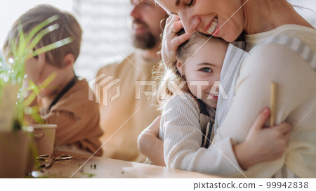 Happy family planting herbs together at spring, mother hugging her little daughter. Happy family planting herbs together at spring, mother hugging her little daughter. 99942838