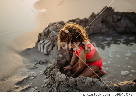 Little girl playing on the beach, digging hole in sand. Little girl playing on the beach, digging hole in sand. 99943078