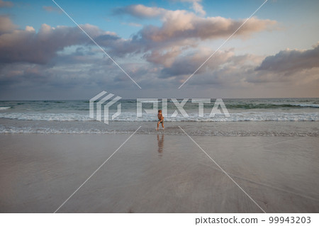 Little boy in swimsuit running out of sea, enjoying holiday. 99943203