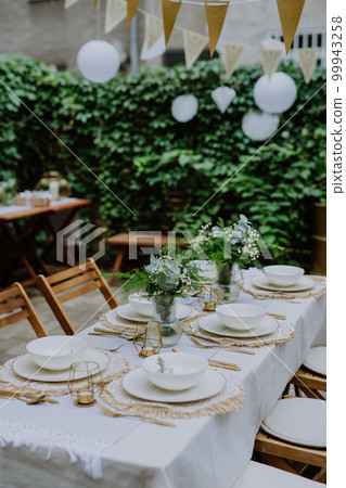 Festive wedding table setting with flowers at small reception in backyard in summer. Festive wedding table setting with flowers at small reception in backyard in summer. 99943258