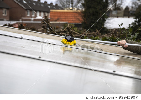 Washing the patio pergola roof cover made of aluminum. removing the dirty algae with brush soap and water close up in garden from a house terrace 99943907