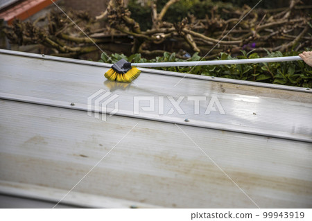 Washing the patio pergola roof cover made of aluminum. removing the dirty algae with brush soap and water close up in garden from a house terrace 99943919