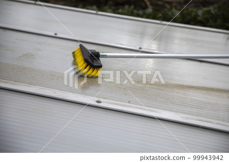 Washing the patio pergola roof cover made of aluminum. removing the dirty algae with brush soap and water close up in garden from a house terrace 99943942
