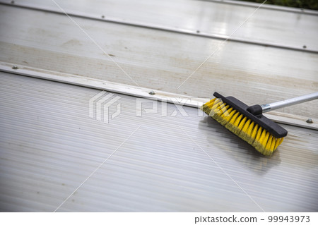 Washing the patio pergola roof cover made of aluminum. removing the dirty algae with brush soap and water close up in garden from a house terrace 99943973