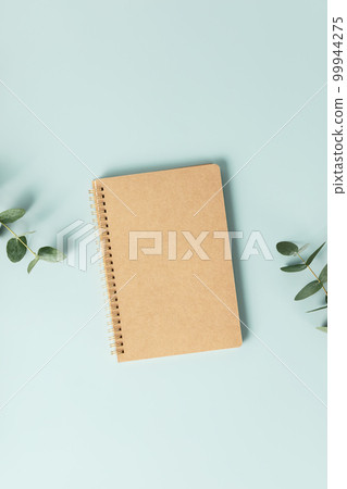 Notebook and flowers on blue background. Flat lay top view copy space mockup 99944275