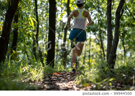 Fitness woman trail runner running in summer forest trail 99944500