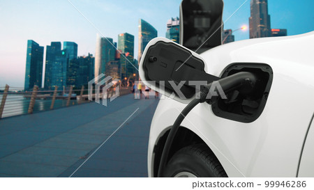 Progressive EV car charging battery from charging point in city area with people 99946286