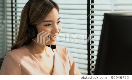 Competent female operator working on computer and while talking with clients. 99946733
