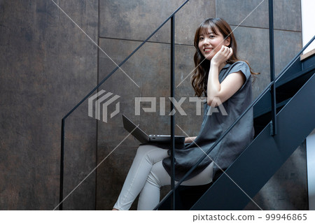 Woman using laptop on stairs 99946865