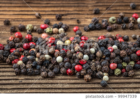 Peppercorns on dark rustic wooden background. Mix of different peppers Peppercorns on dark rustic wooden background. Mix of different peppers 99947339