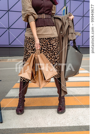A beautiful girl with shopping bags is walking along a pedestrian crosswalk. Consumerism, shopping, shopping, lifestyle concept 99949677