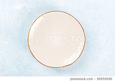 An empty white plate with a gold rim, overhead flat lay shot 99950090