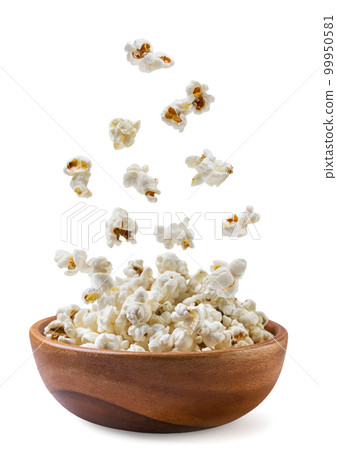 Popcorn falls in a wooden plate close-up on a white background. Isolated 99950581