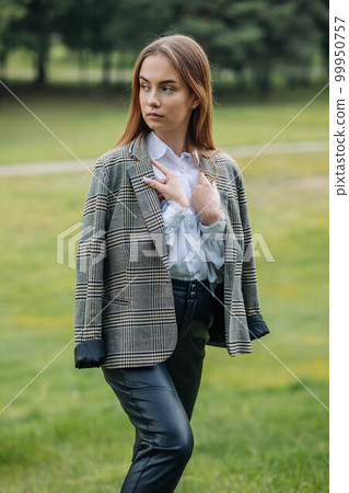 A young girl in a jacket poses in a park in the summer. A young girl in a jacket poses in a park in the summer. 99950757