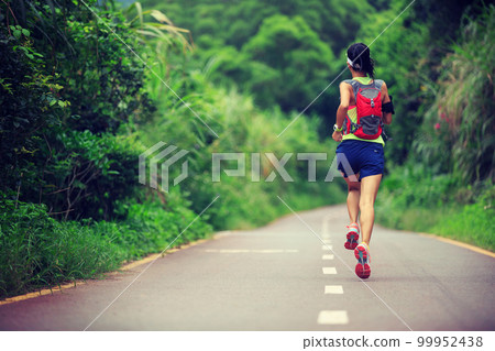 Young fitness woman trail runner running in forest mountain 99952438