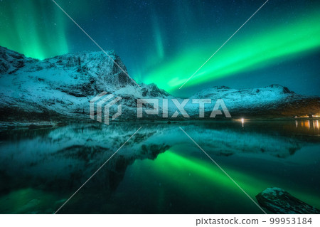 Northern lights over snowy mountains, sea, reflection in water 99953184