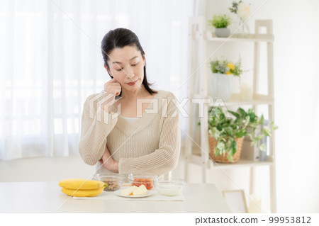 Intestinal activity A middle-aged woman thinking while looking at the ingredients that are good for the intestines on the table Intestinal activity A middle-aged woman thinking while looking at the ingredients that are good for the intestines on the table 99953812
