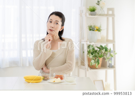 Intestinal activity A middle-aged woman thinking while looking at the ingredients that are good for the intestines on the table Intestinal activity A middle-aged woman thinking while looking at the ingredients that are good for the intestines on the table 99953813