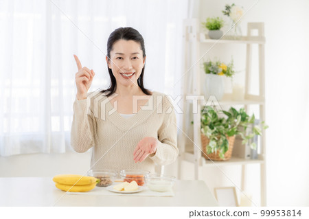 腸道活動 一位中年婦女在餐桌上介紹對腸道有益的食材 腸道活動 一位中年婦女在餐桌上介紹對腸道有益的食材 99953814