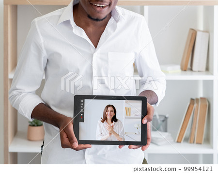 E-learning class. Video call. Digital education. Male student showing online lesson with female teacher on tablet screen at home interior. 99954121