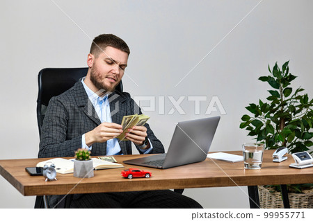 young bearded businessman working on laptop and holding money 99955771
