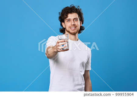 handsome man in a white t-shirt showing drinking glass of water handsome man in a white t-shirt showing drinking glass of water 99955904