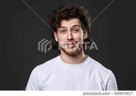 skeptic and nervous man in white t-shirt on dark gray background skeptic and nervous man in white t-shirt on dark gray background 99955927