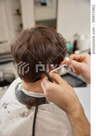 young caucasian man getting haircut by professional male hairstylist 99955962