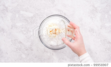 Flat lay. Step by step. Mixing ingredients in a glass mixing bowl to prepare cream cheese frosting. 99958907